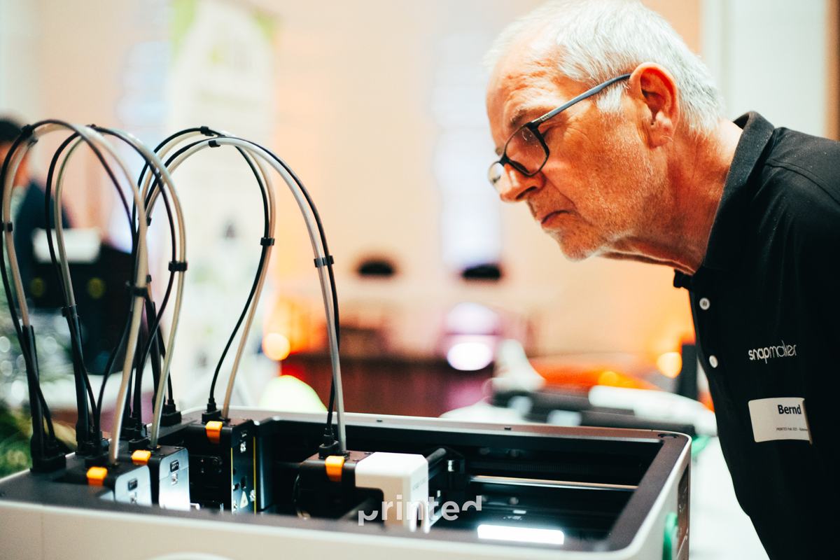 An attendee looking closely at a printer's toolhead